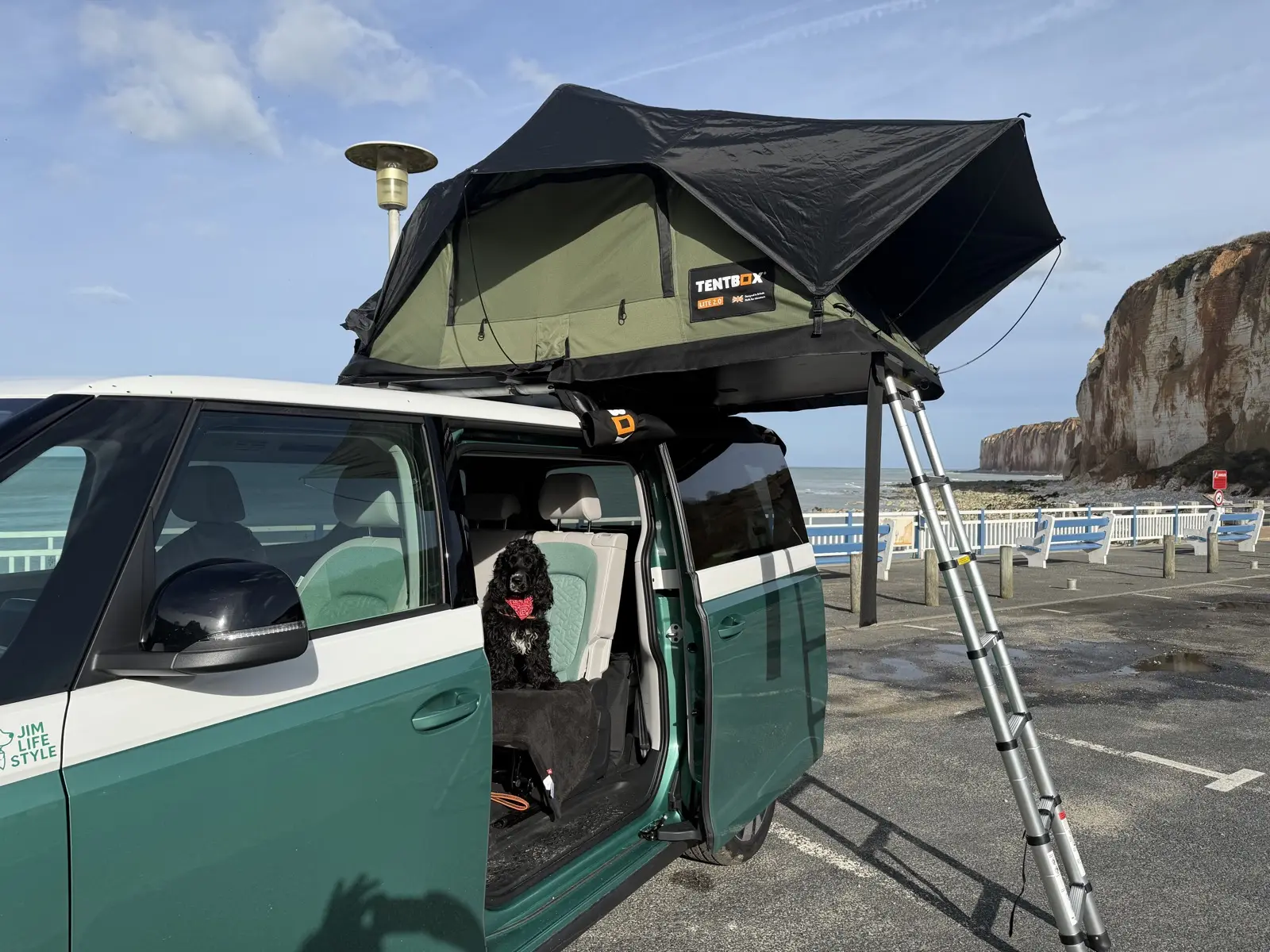 Le van Volkswagen ID. Buzz portière ouverte, Jim le cocker à l'intérieur, falaises d'Étretat en fond
